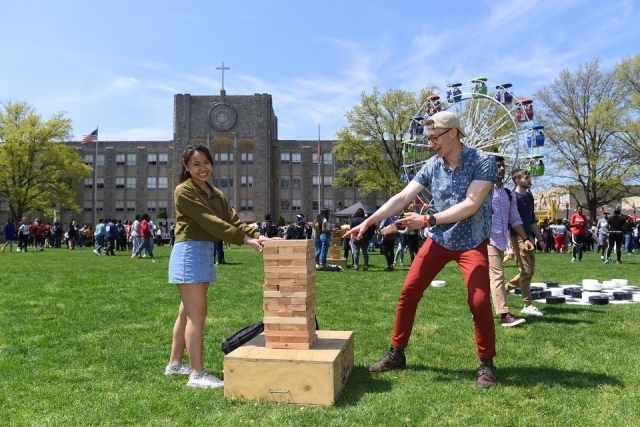 St. John's University students playing giant jenga at the Spring Carnival in the Queen Campus’ St. Augustine Plaza